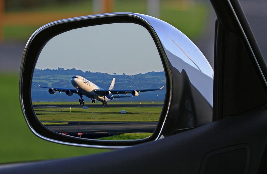 Flygplan syns i sidospegel på bil.
